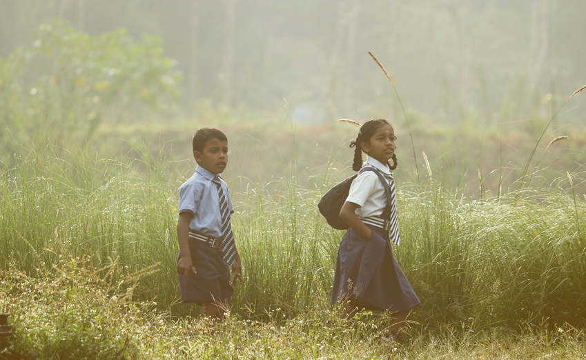 Children walking through a field on their way to school